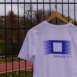 Weißes T-Shirt mit ORANGE-Logo am Sportplatz